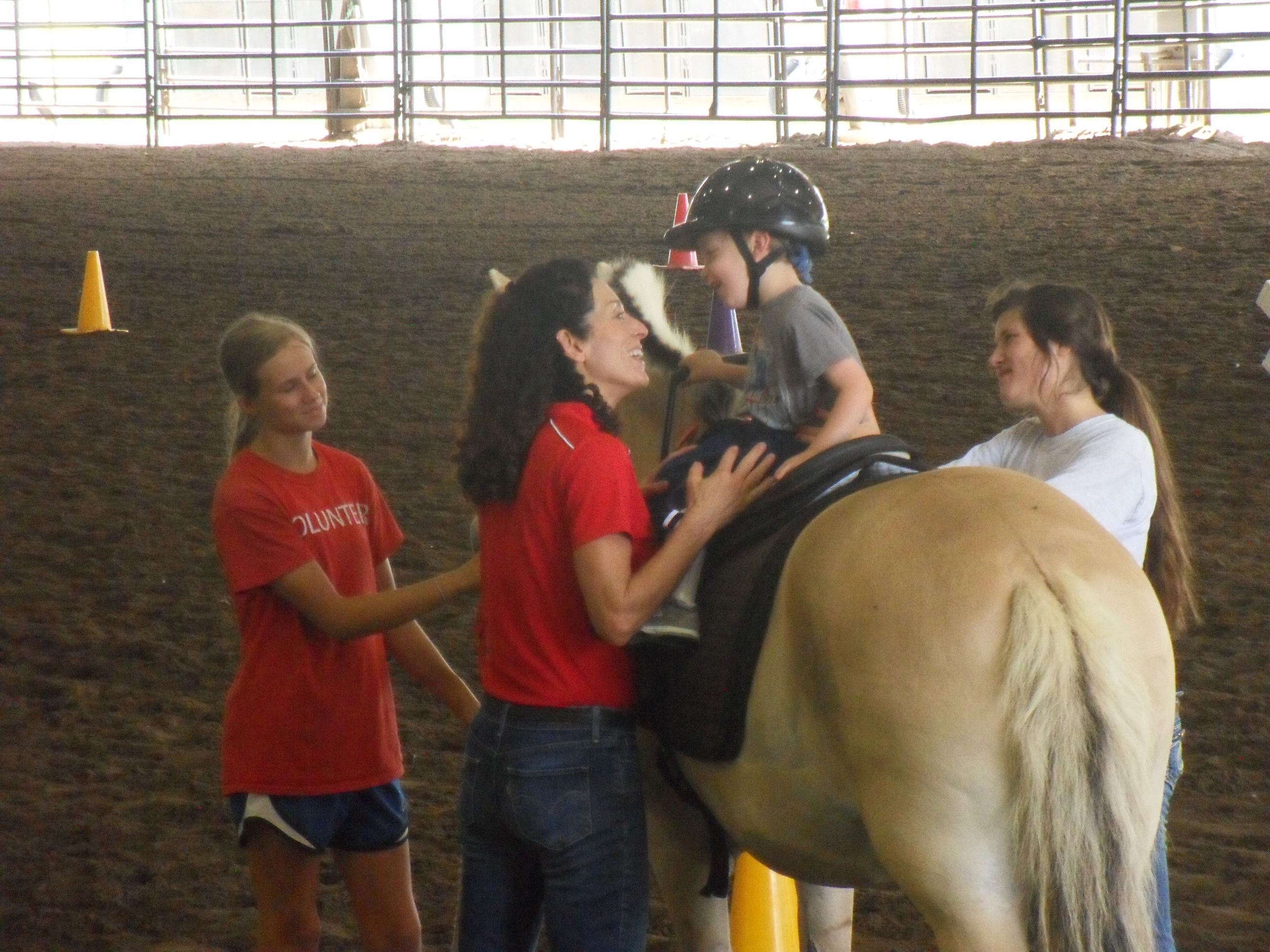 Woman helping child off of a horse