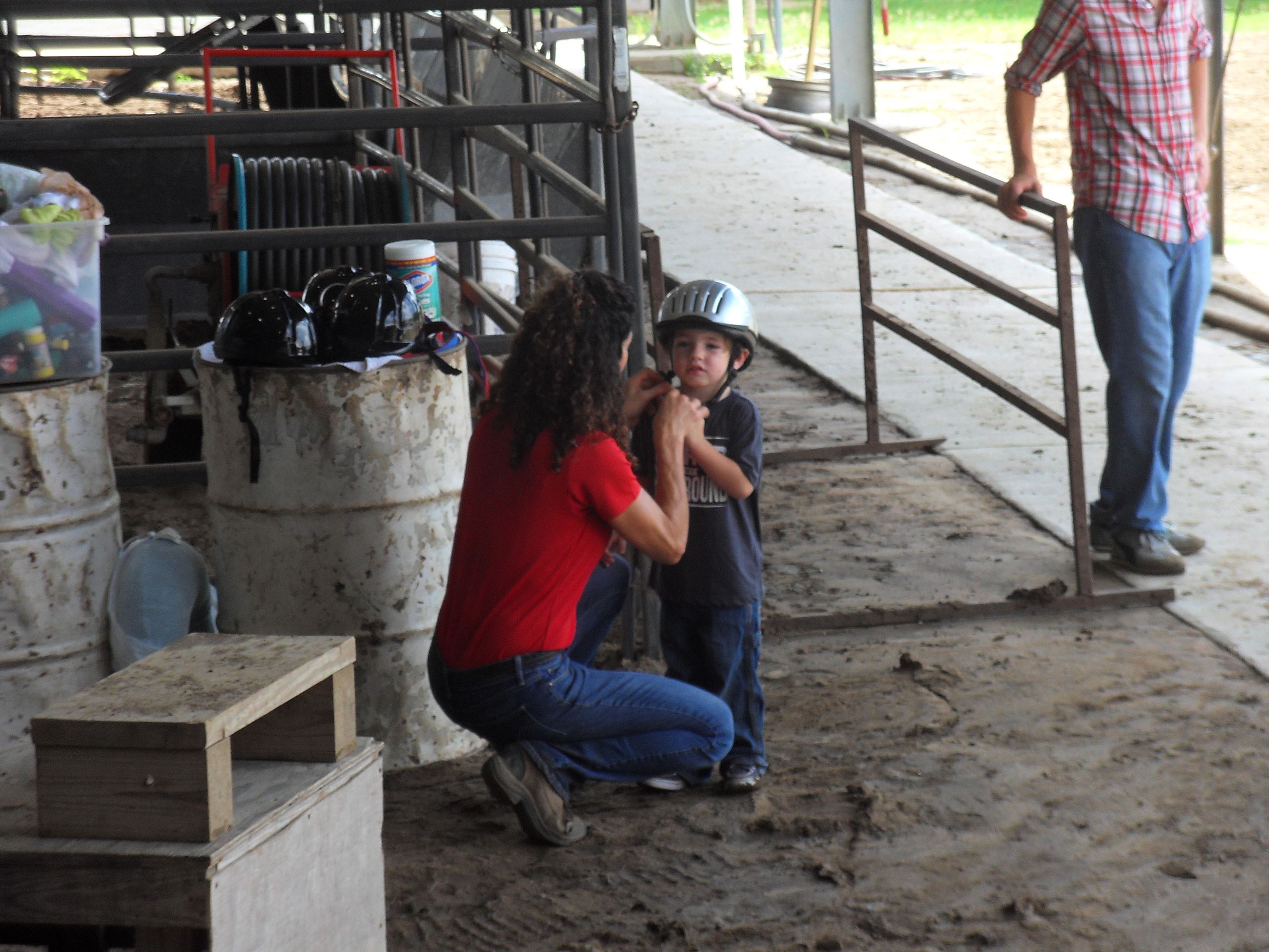Woman putting a riding helmet onto a child